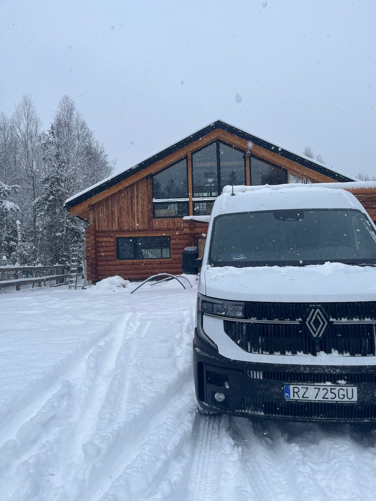 Samochód WOB-Tech przed domem z bali